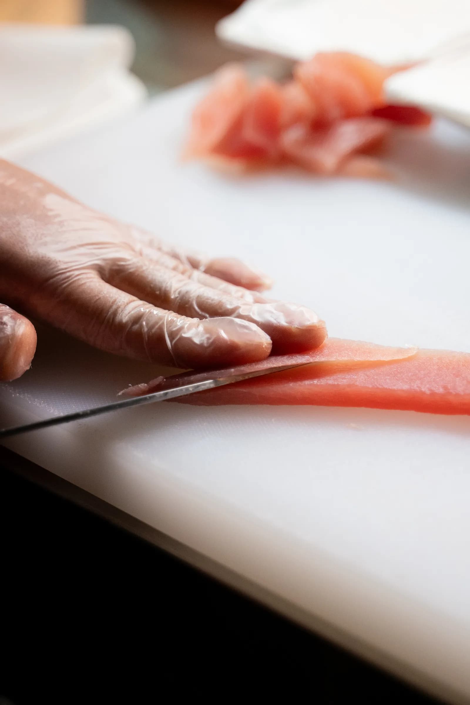 Mano che taglia a fette un trancio di tonno sul tagliere