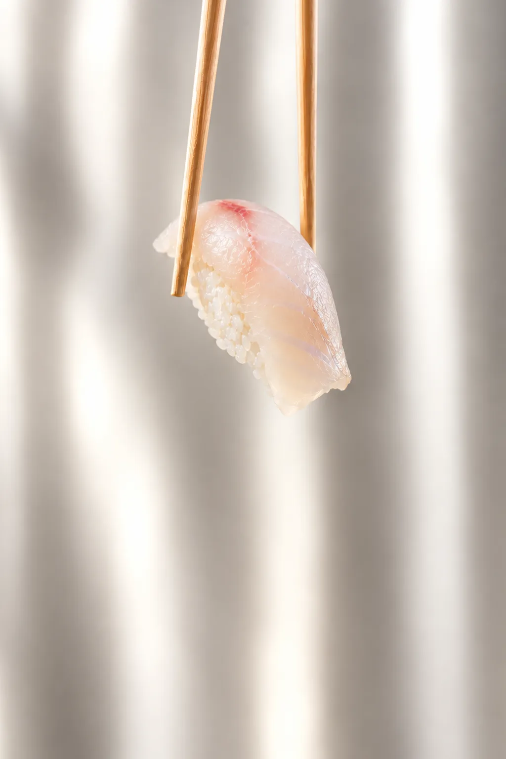 Nigiri di pesce bianco tenuto con le bacchette